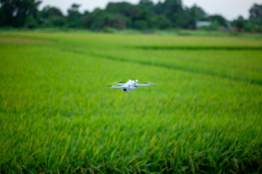 A drone hovering above a vibrant green agricultural field, showcasing modern farming technology.